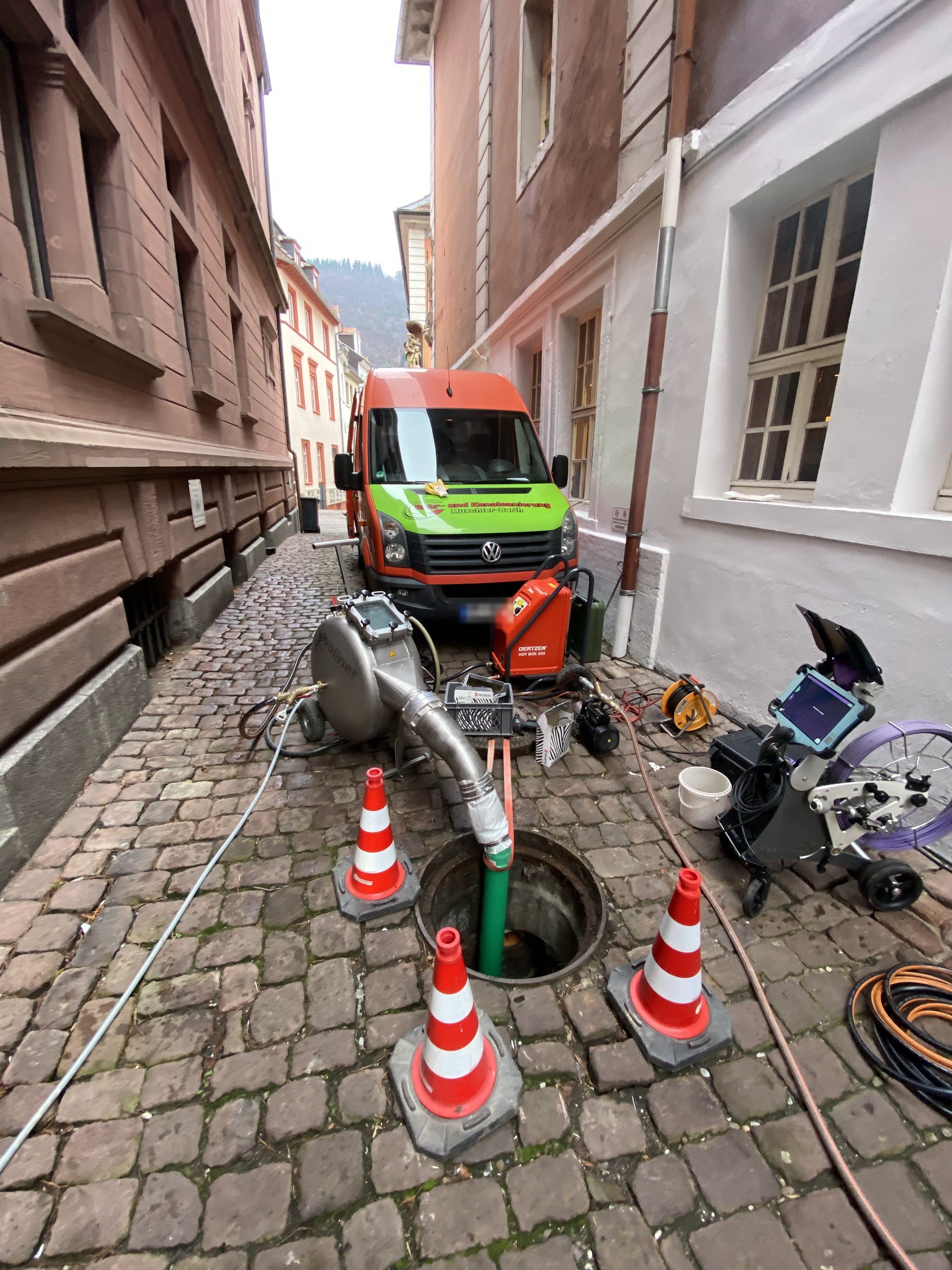 Einsatz in einer engen Altstadtgasse: Firmenwagen, Pylonen und Saugtechnik am offenen Schacht